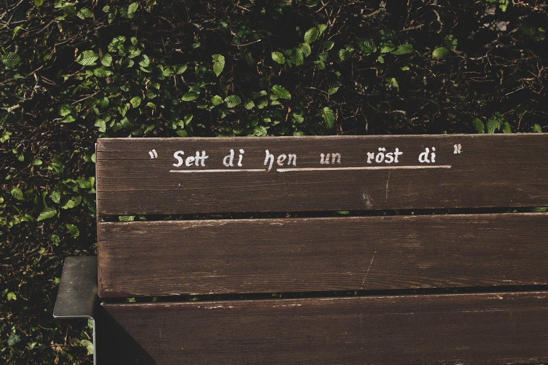 a wooden bench sitting in front of a bush