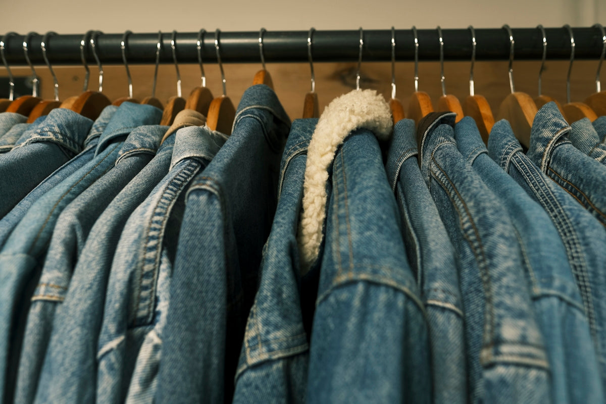 a pile of blue jeans hanging on a rail