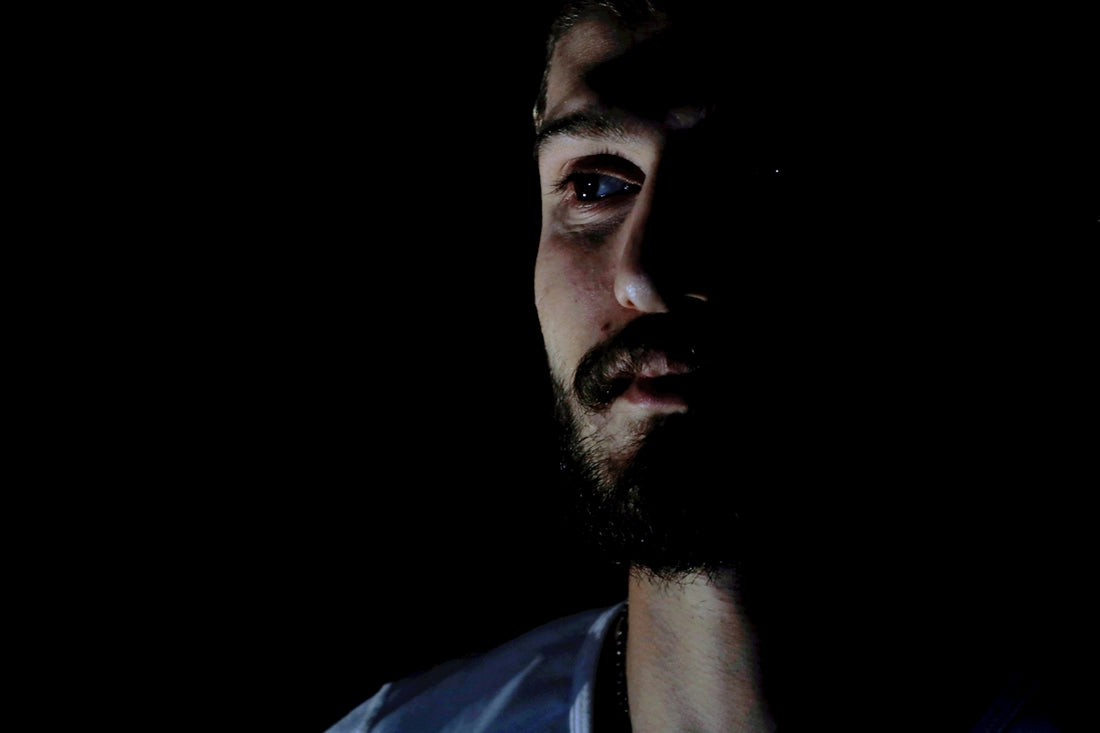 a man with a beard and blue shirt in the dark