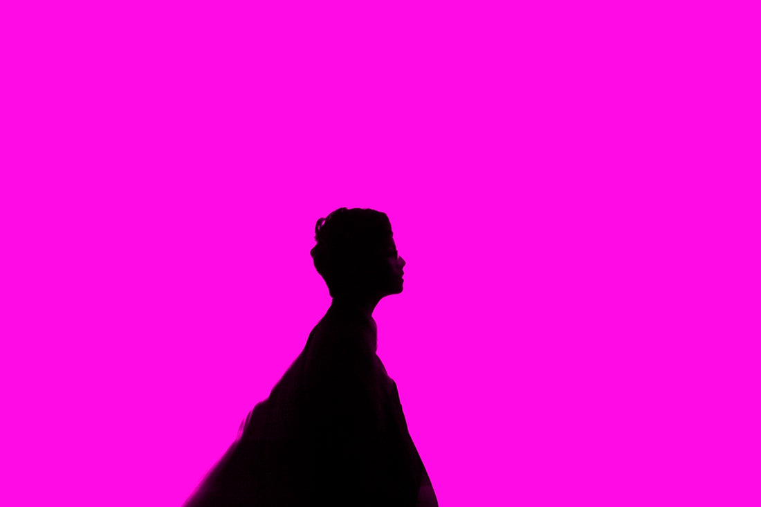 Silhouette of a person against a pink background.