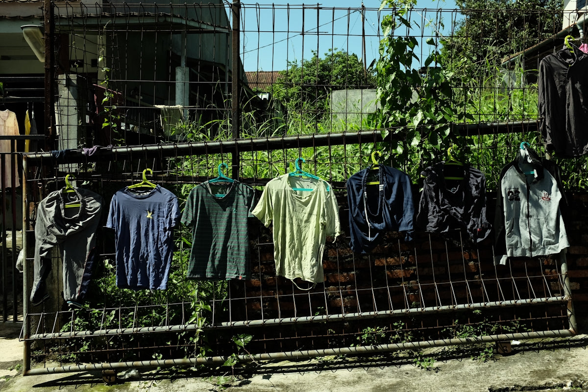 Clothes hang on a fence outside.