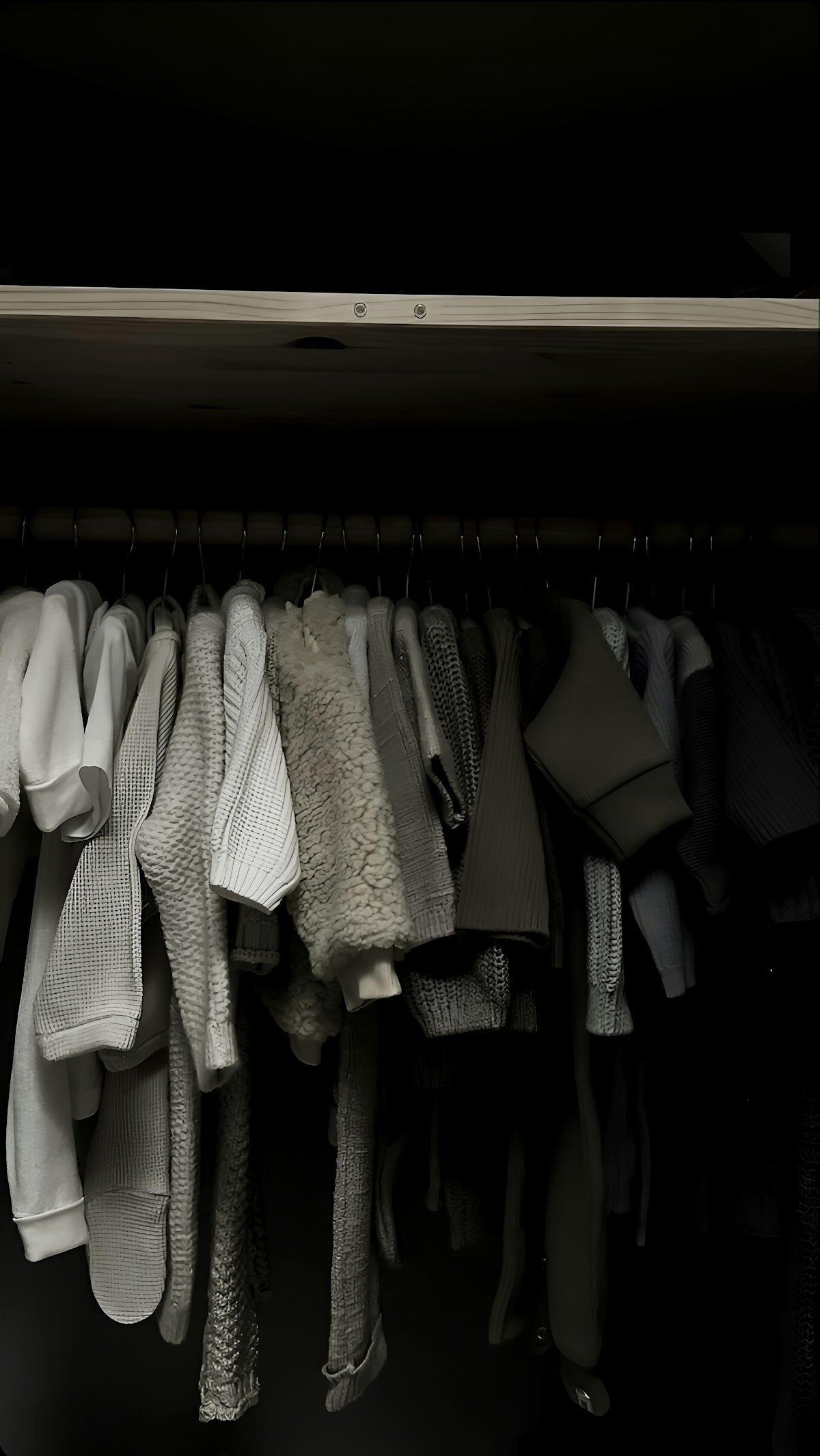 Baby clothes hanging in a dark closet