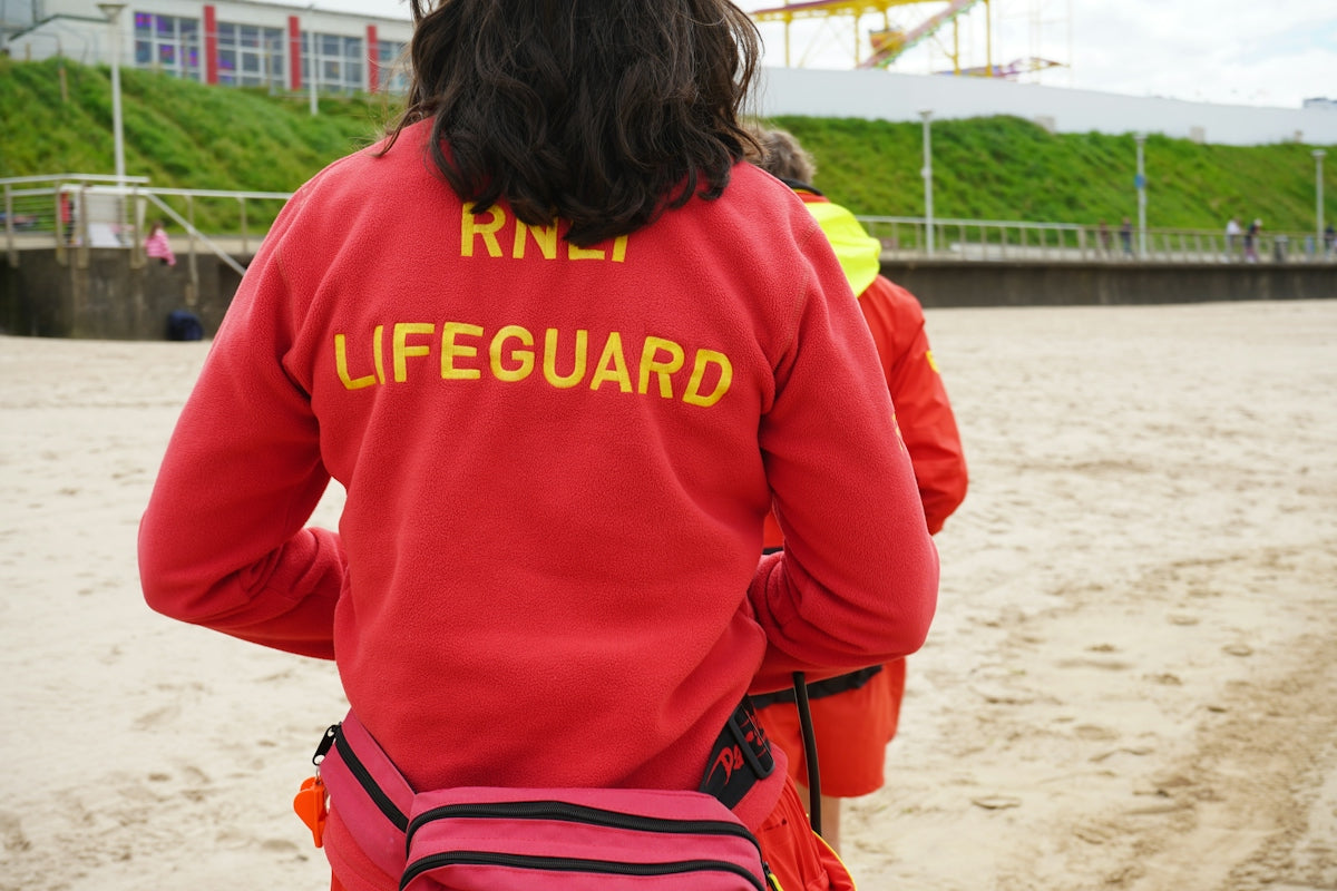 A lifeguard walks on a sandy beach